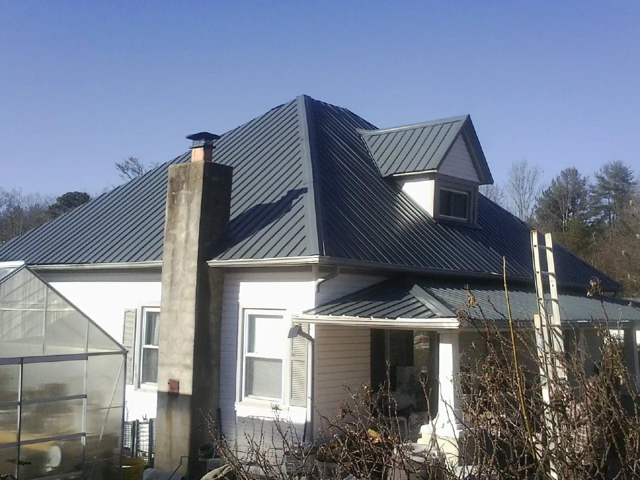Dark blue standing seam metal roof on a white farmhouse with dormer — Slate & Tile Roof Repair by Roofing Brothers in Spokane