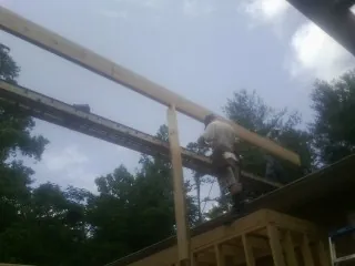 Carpenter setting a ridge beam over a new addition frame — Ice Dam Removal by Roofing Brothers in Spokane