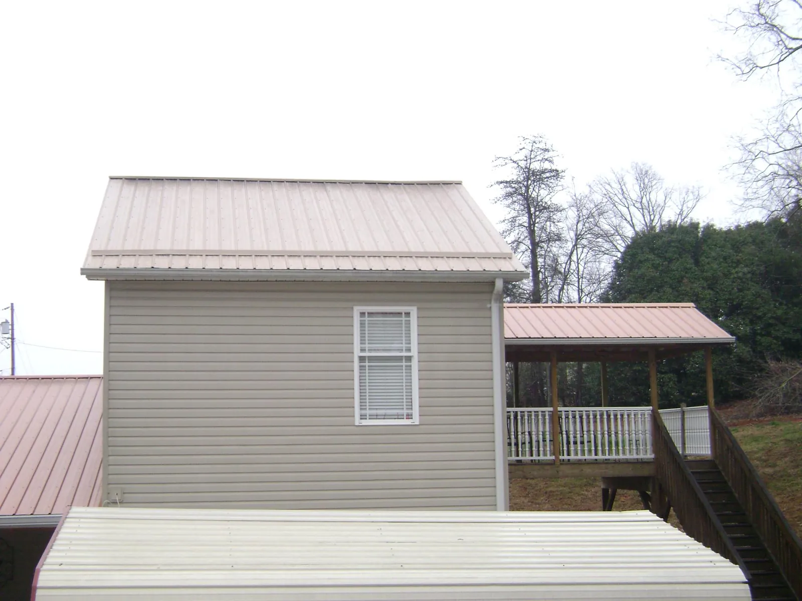 Tan metal roofs on a two story addition and attached porch, from a Roof Replacement job in Spokane