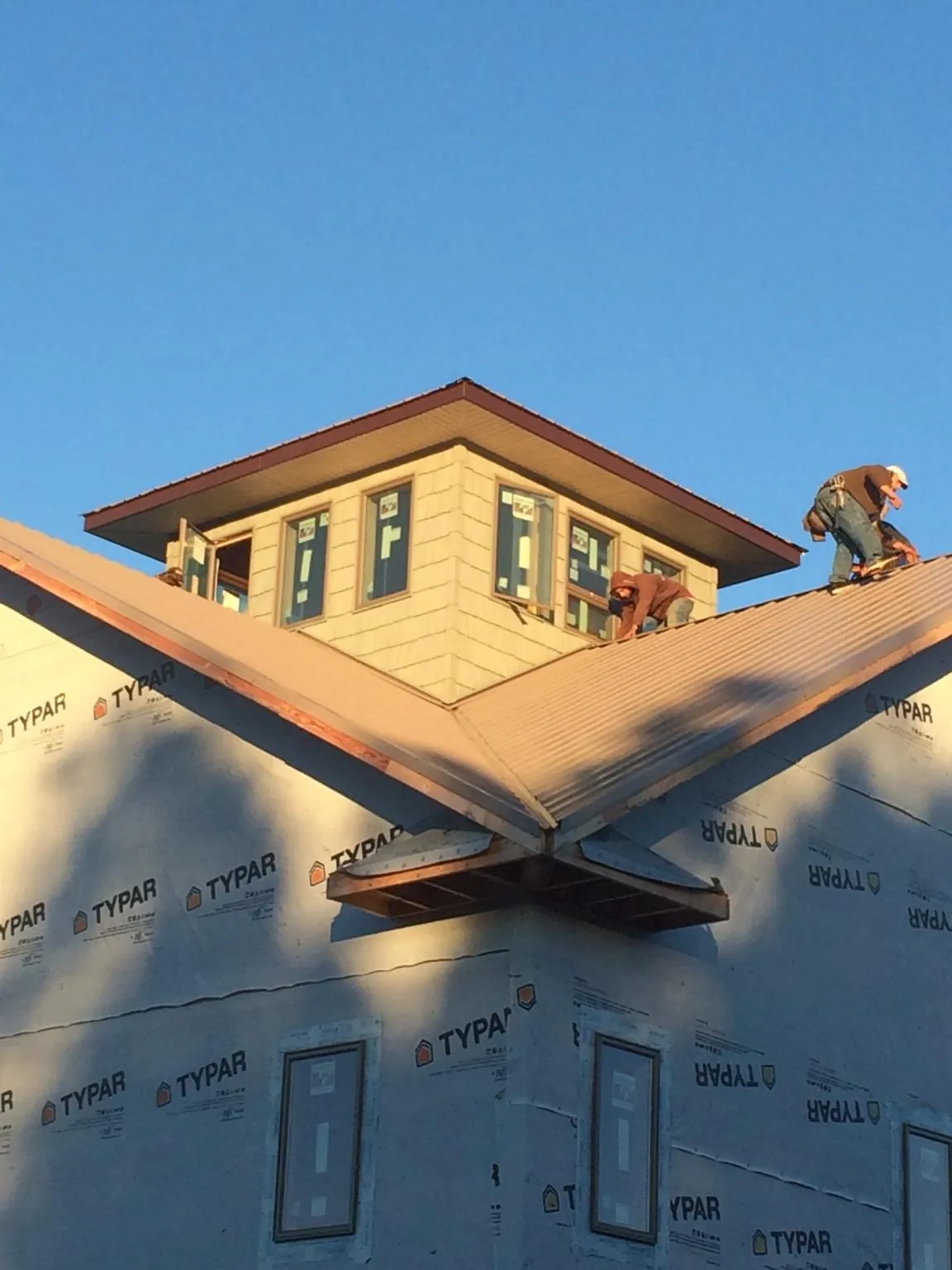 Roofers working around a rooftop cupola on a new metal roof at sunset — Roof Waterproofing in Spokane by Roofing Brothers